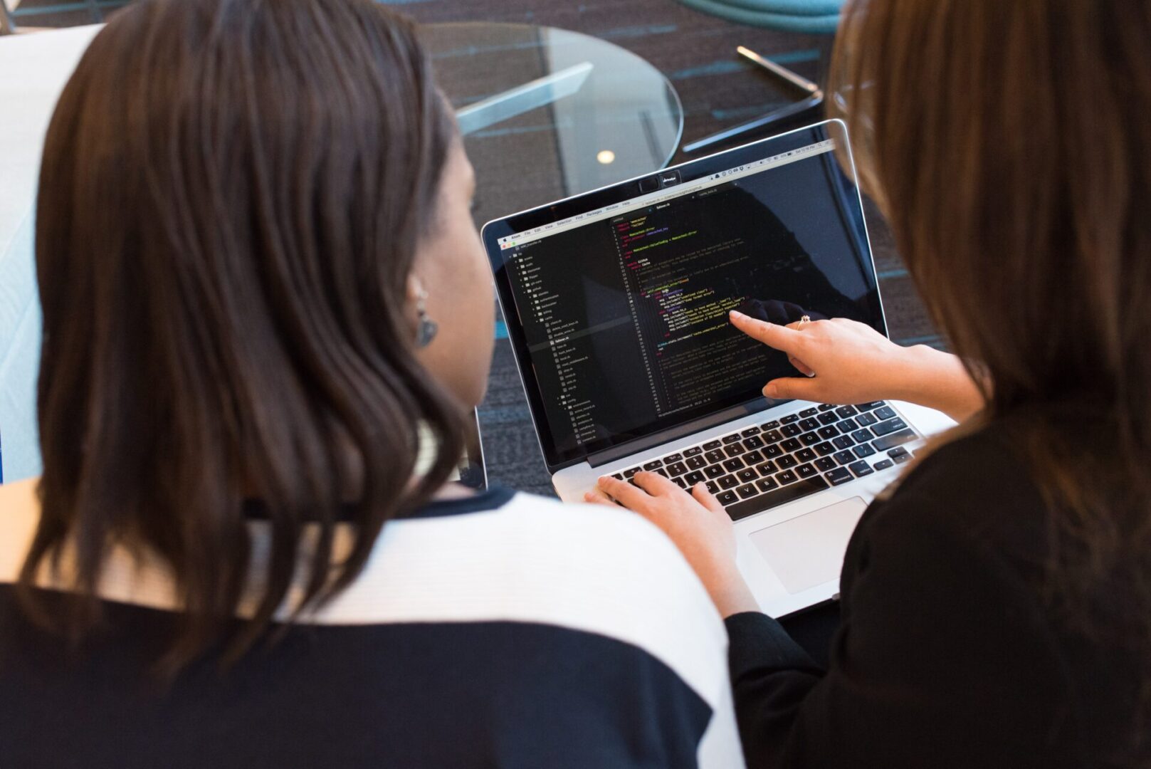 Two women are using a laptop computer.