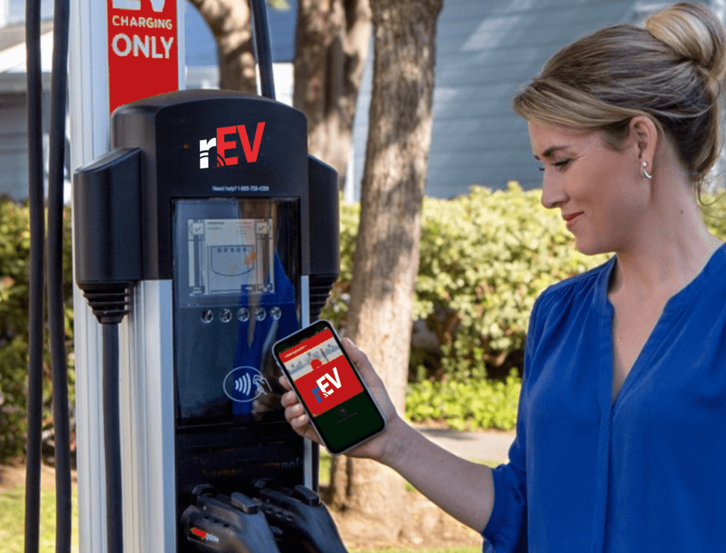 A woman is holding her phone and looking at the parking meter.