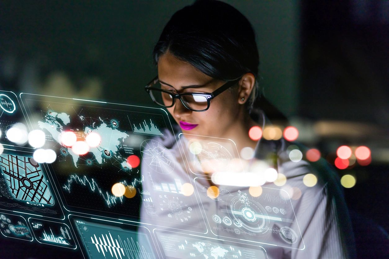 A woman in glasses is looking at her laptop.