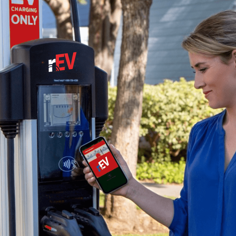 A woman is holding her phone and looking at the parking meter.
