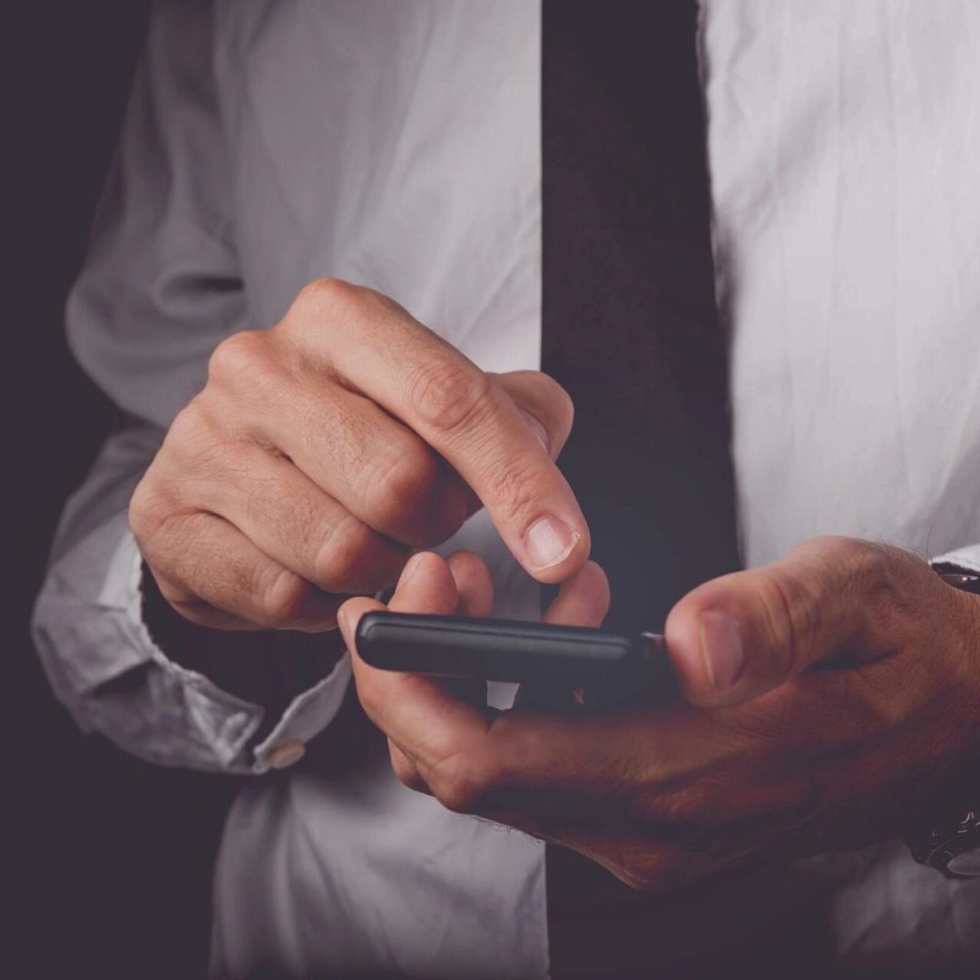 A man in a white shirt and tie holding a phone.